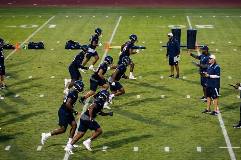 Football players training on practice field during preseason preparation