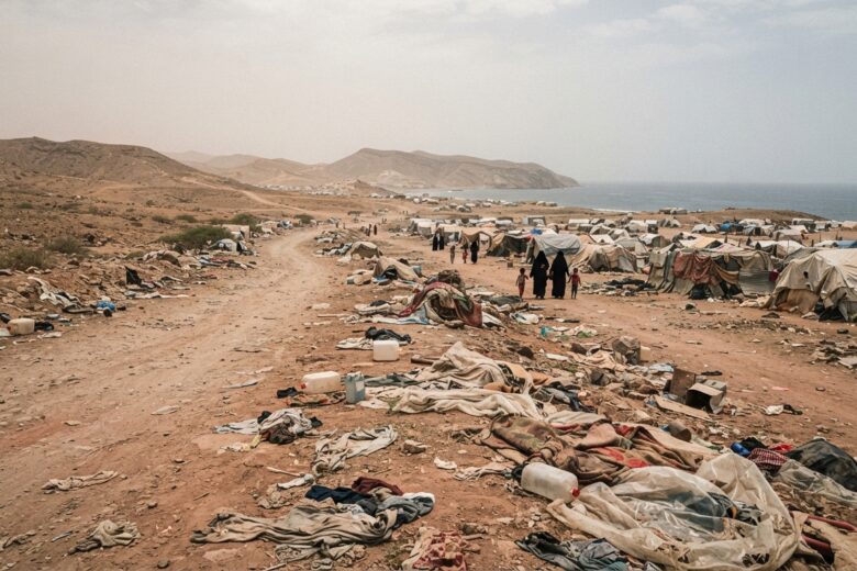 Makeshift displacement camp along a desert road in coastal Yemen showing humanitarian crisis conditions